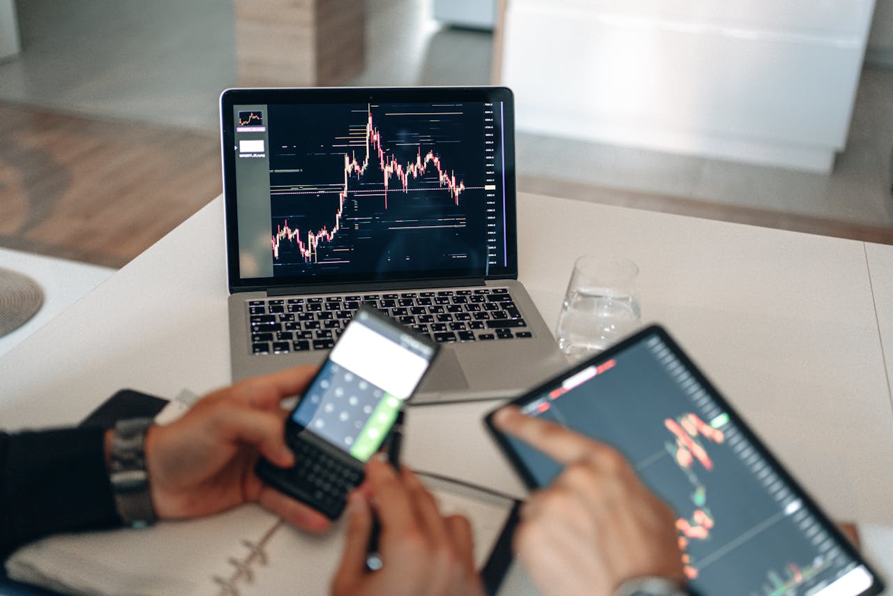 about-01 Hands using digital devices for financial analysis at a modern desk setup.